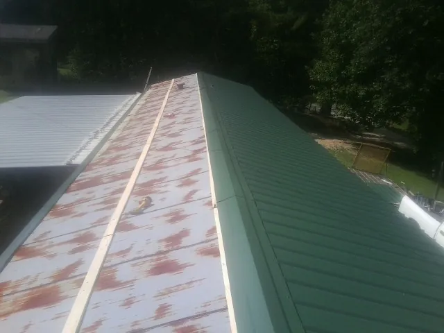 Old rusted panels beside newly installed green metal roofing — Wind Damage Roof Repair by Roofing Brothers in Rehoboth Beach
