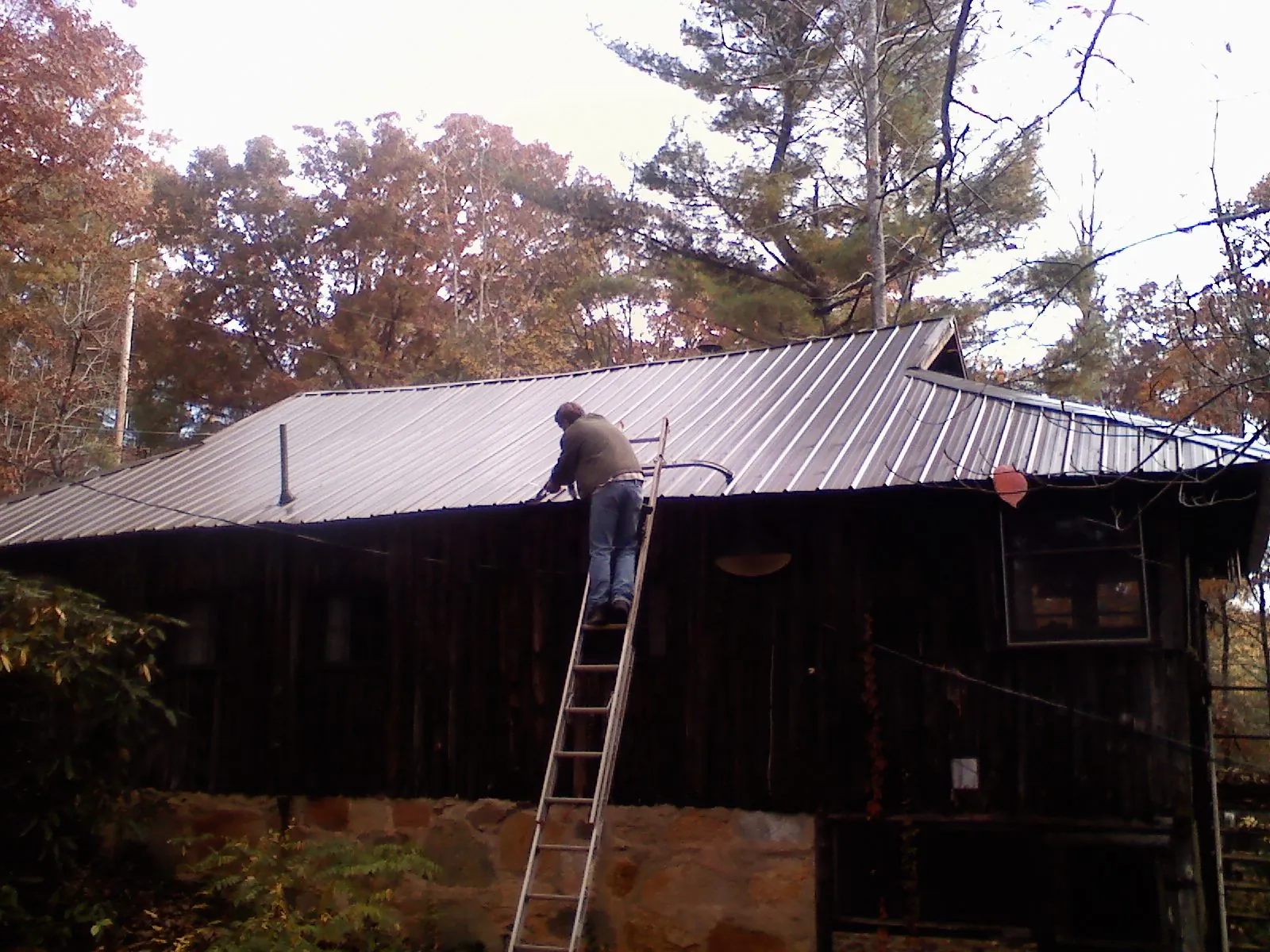 Roofer on a ladder working along the edge of a cabin metal roof in Rehoboth Beach
