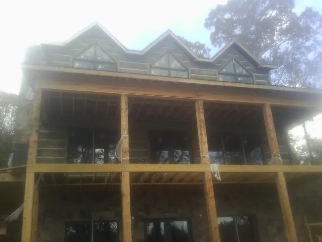 Dormers and porch framing on a large log home under construction — Roof Coating work by our crew in Rehoboth Beach