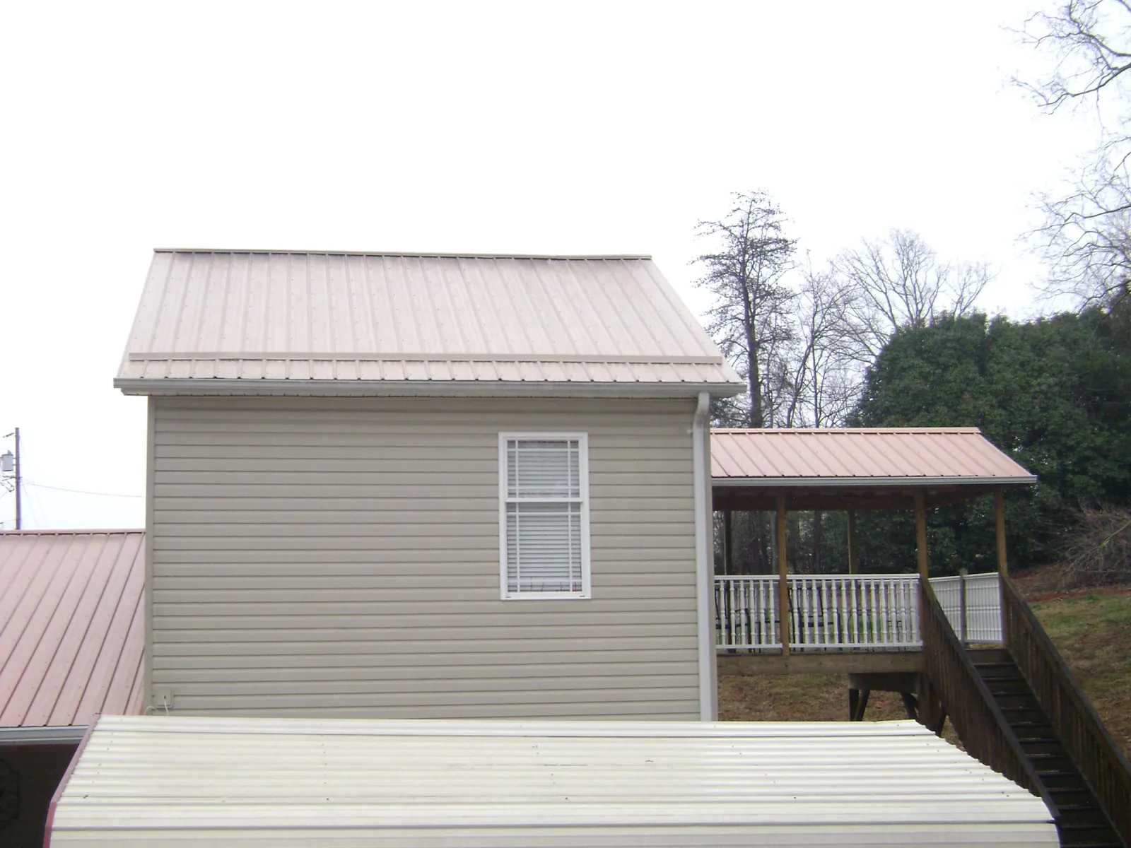 Tan metal roofs on a two story addition and attached porch, from a Roof Replacement job in Rehoboth Beach