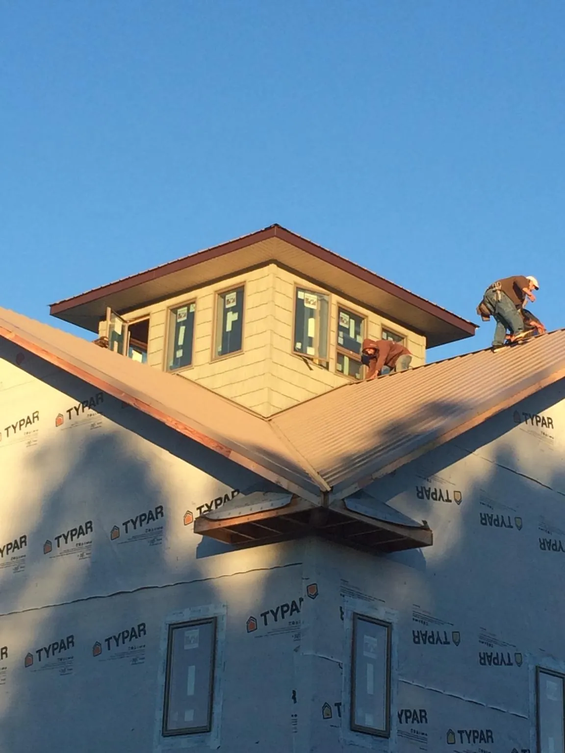 Roofers working around a rooftop cupola on a new metal roof at sunset — Roof Waterproofing in Rehoboth Beach by Roofing Brothers